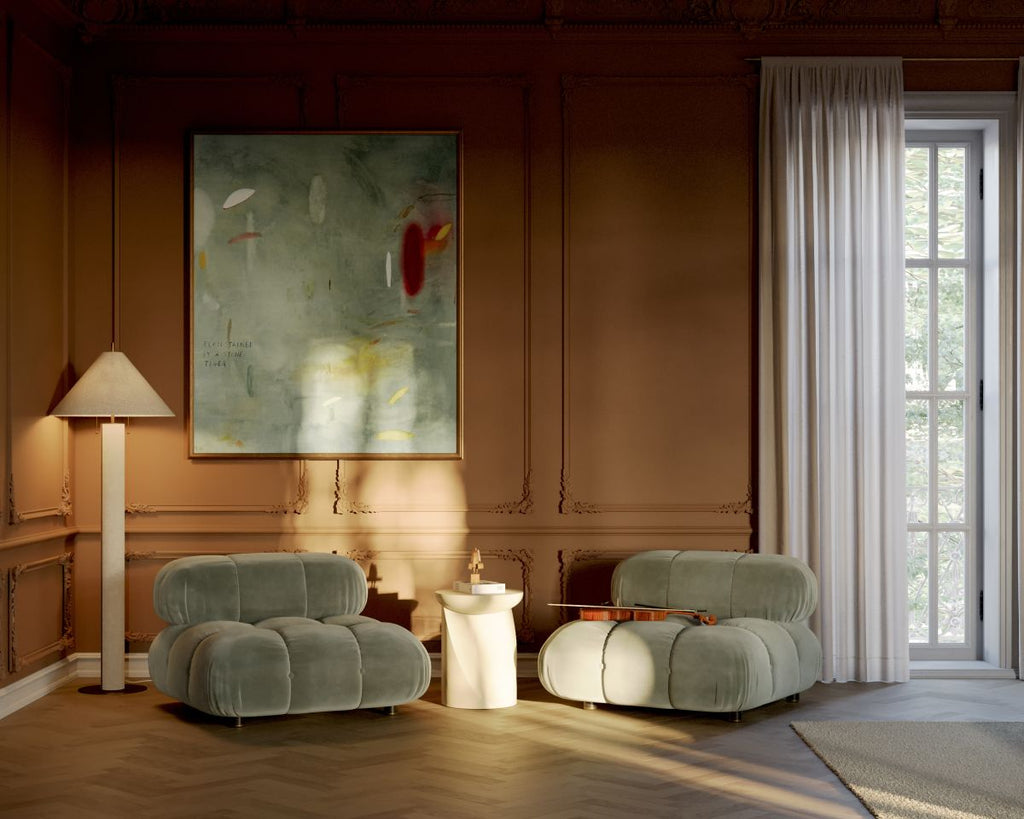 Modern living room with two green armchairs, a lamp, and abstract art on the wall.