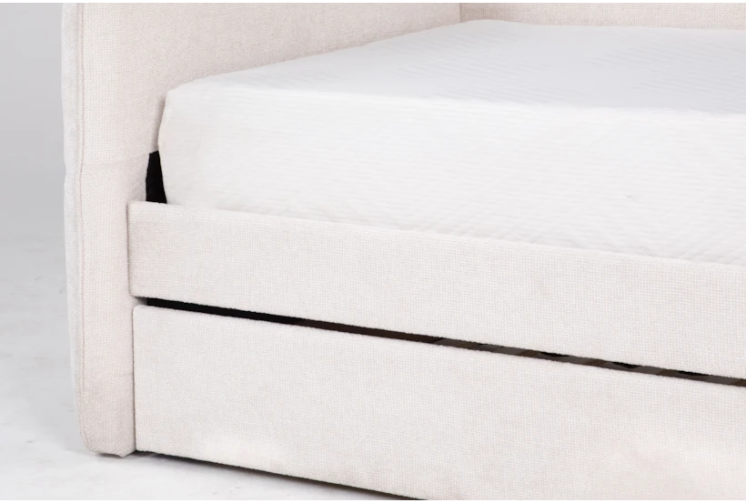 Close-up of a white upholstered bed frame with a mattress on a light gray background