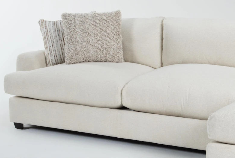 Beige sofa with two pillows on a white background
