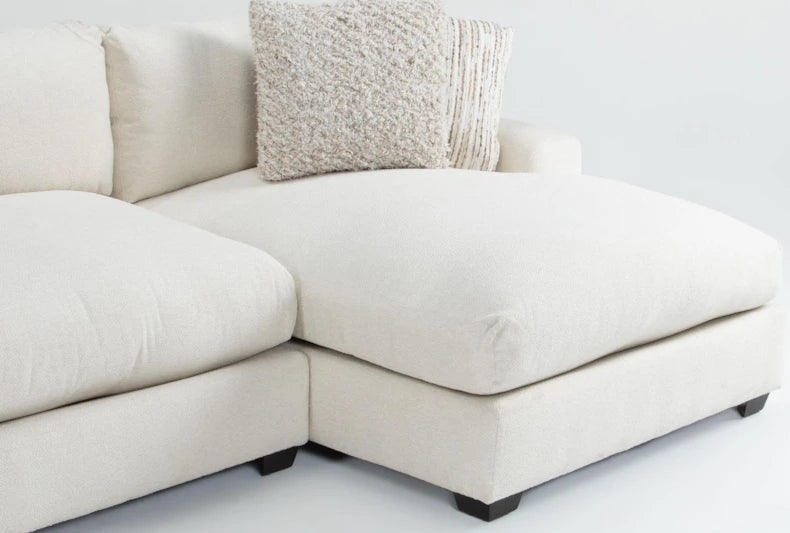 White sectional sofa with a textured pillow on a light gray background