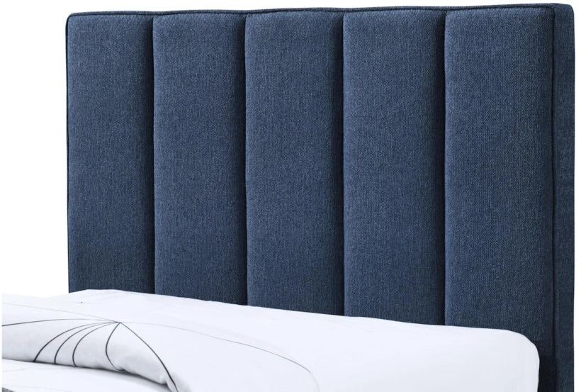 Blue upholstered headboard on a bed with white bedding