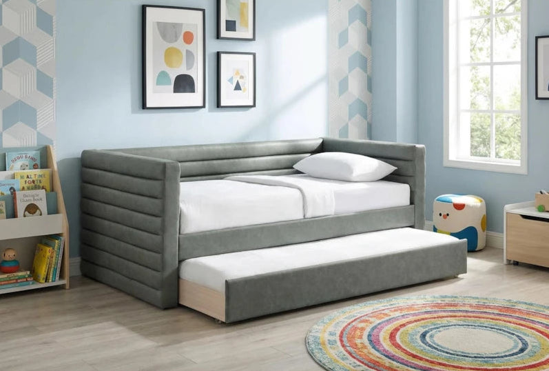 Gray upholstered bed with white bedding in a child-friendly room with toys and books.