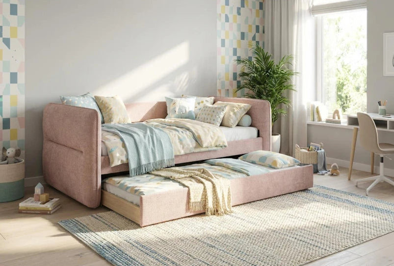 Pink sofa bed in a room with a desk and plants