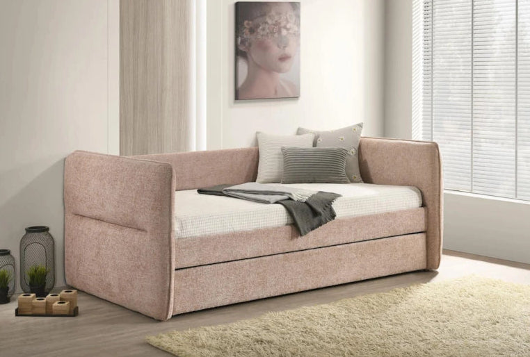Pink sofa bed in a room with a painting on the wall and a window.