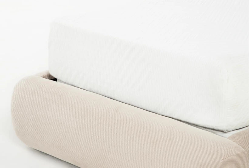 Close-up of a beige fabric headboard against a white wall