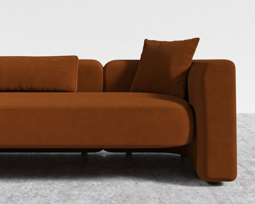 Brown sofa with a pillow on a gray floor