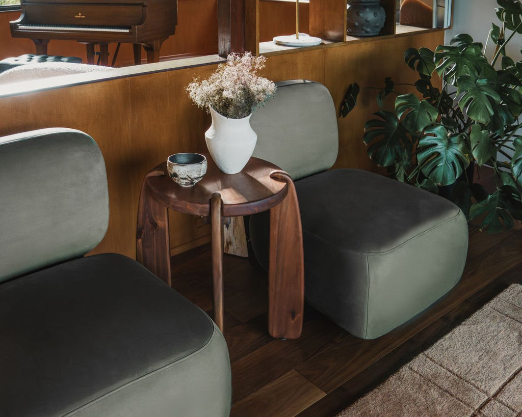 Gray cushioned chairs with a wooden side table and decorative items in a room.