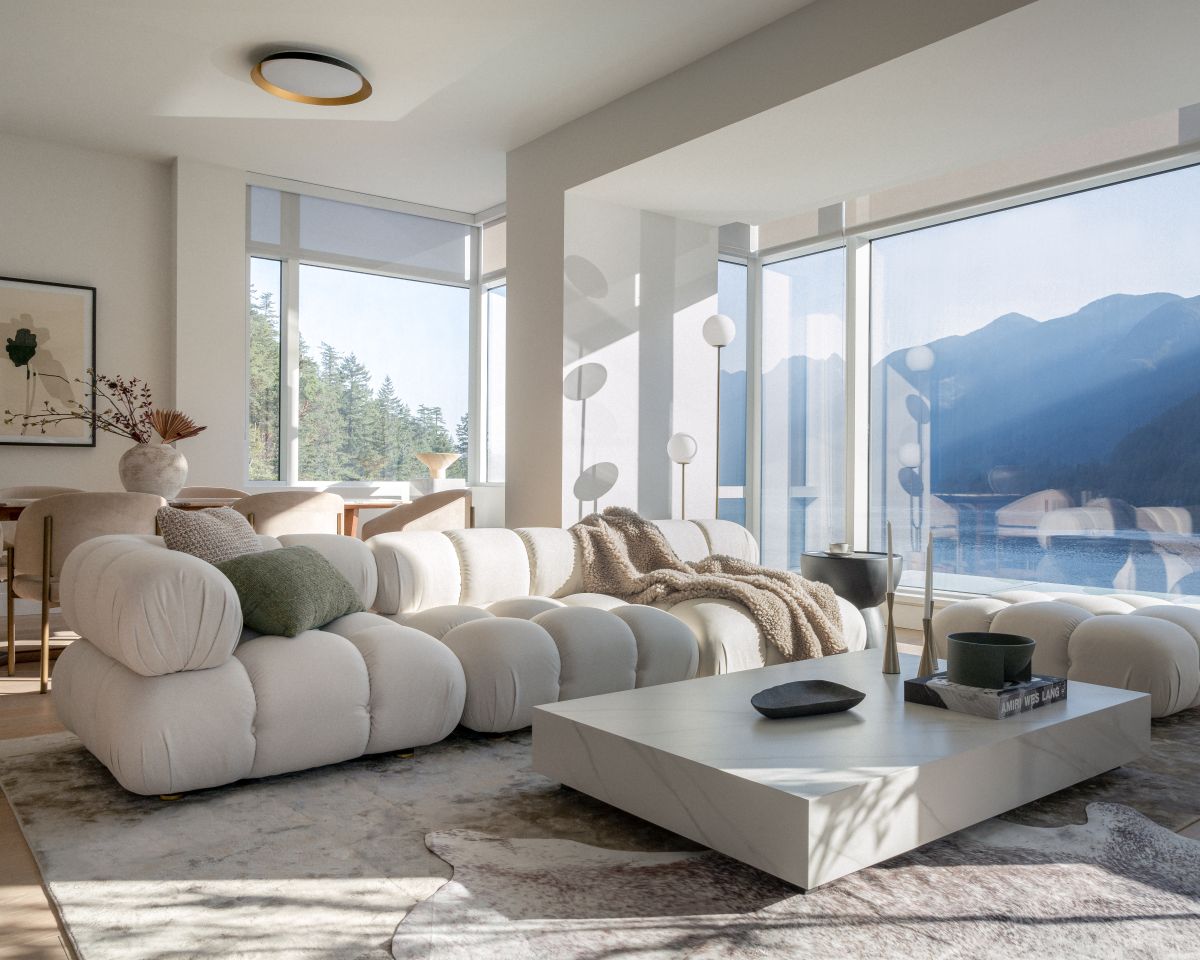 Modern living room with a large white sofa, coffee table, and scenic window view.