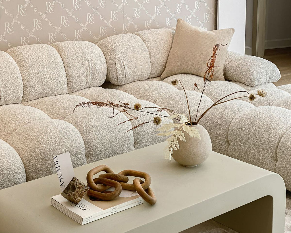 Beige sectional sofa with a coffee table featuring decorative items in a living room.