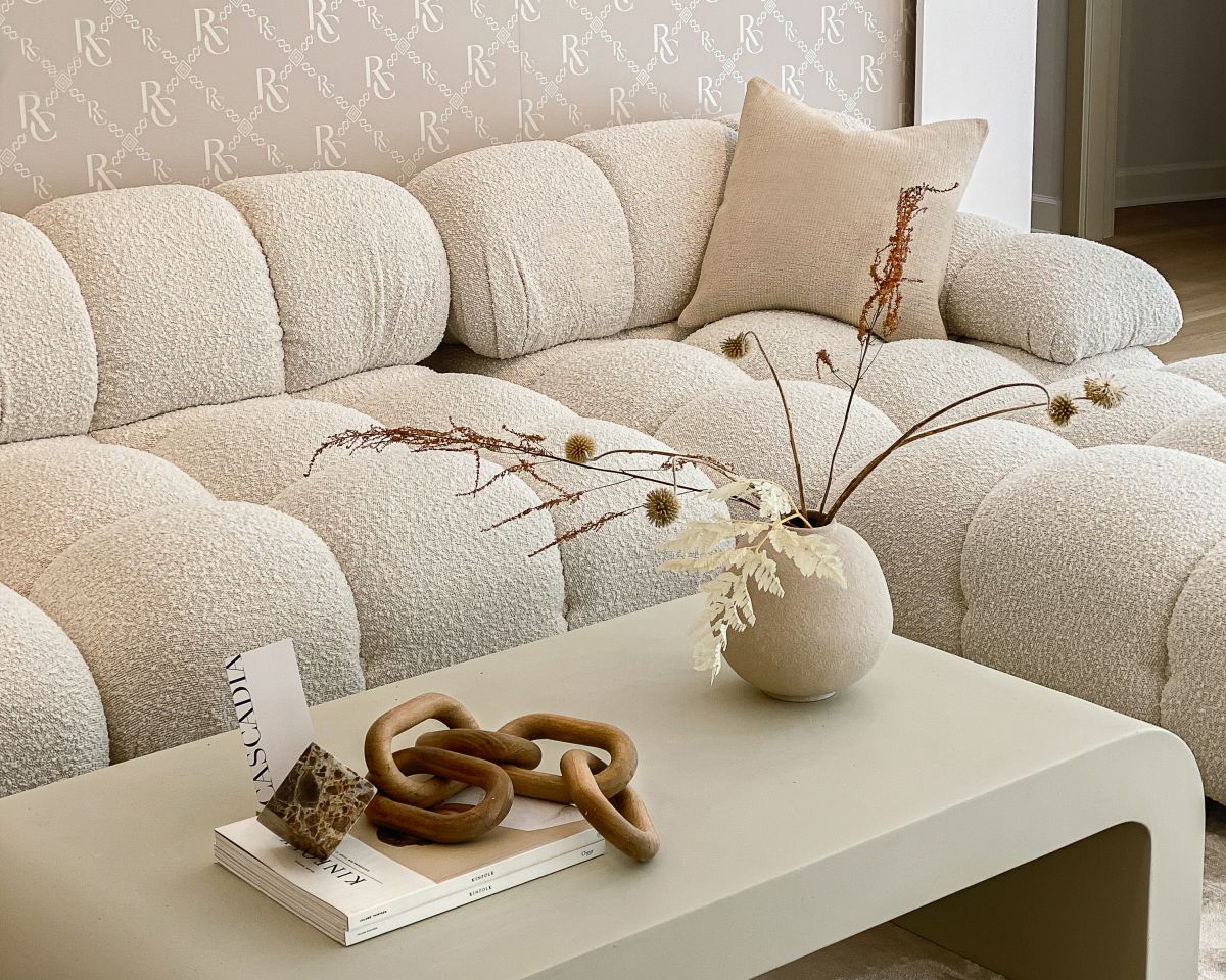 Beige sectional sofa with a coffee table featuring decorative items in a living room.