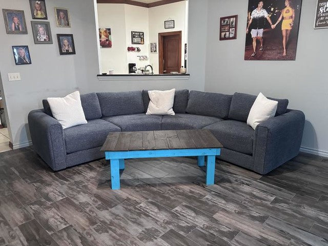 Sectional sofa with a wooden coffee table in a living room setting.